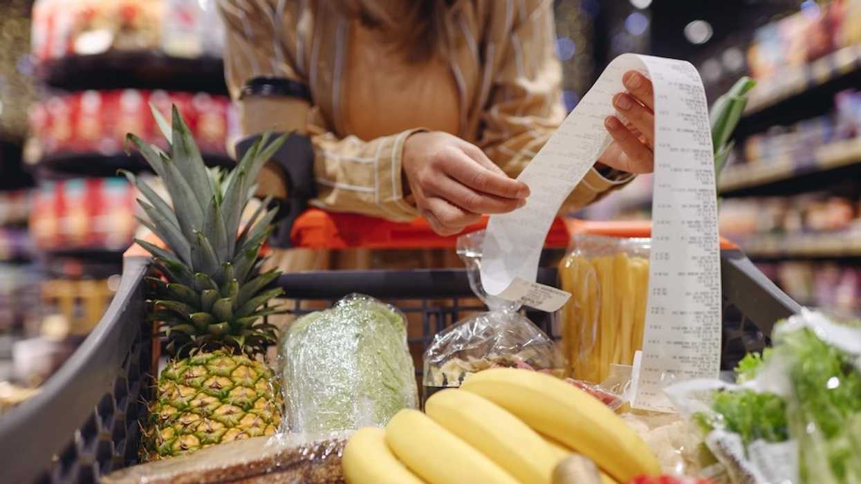 A woman grocery shopping high costs receipt