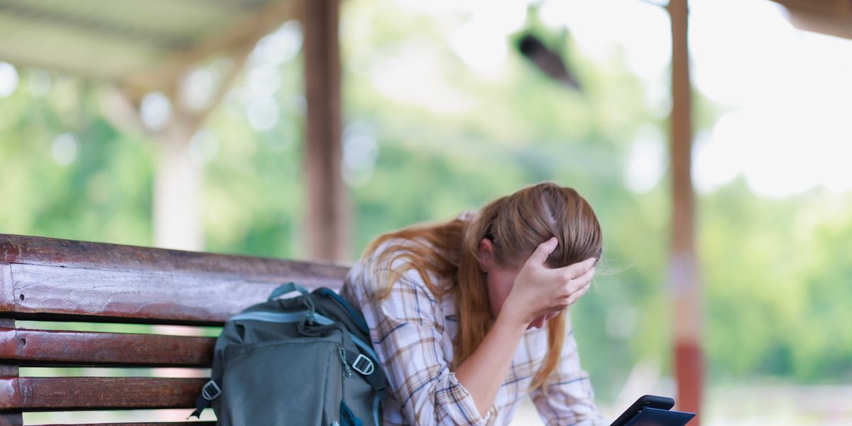 Photo: Alternet A young woman on a bench expresses frustration while checking her phone suwatchai wongaong