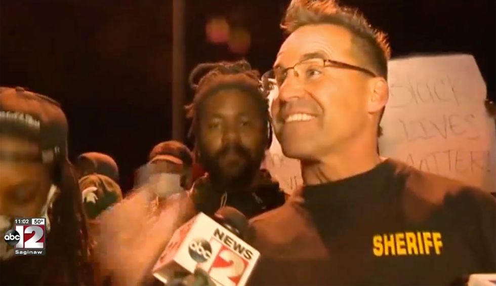 Watch: Michigan sheriff and police didn't use harsh tactics to control Flint Township's protest — they laid down their batons and joined it