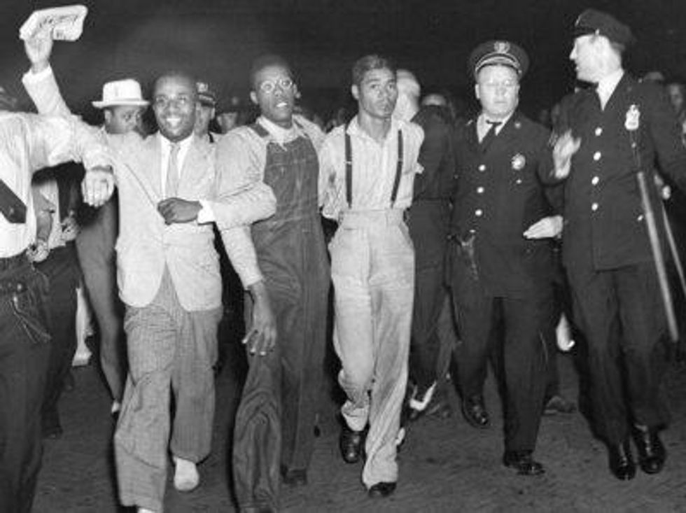In this July 26, 1937 file photo, police escort two of the five recently freed "Scottsboro Boys," Olen Montgomery, wearing glasses, third left, and Eugene Williams, wearing suspenders, fourth left, through the crowd greeting them upon their arrival at Penn Station in New York.