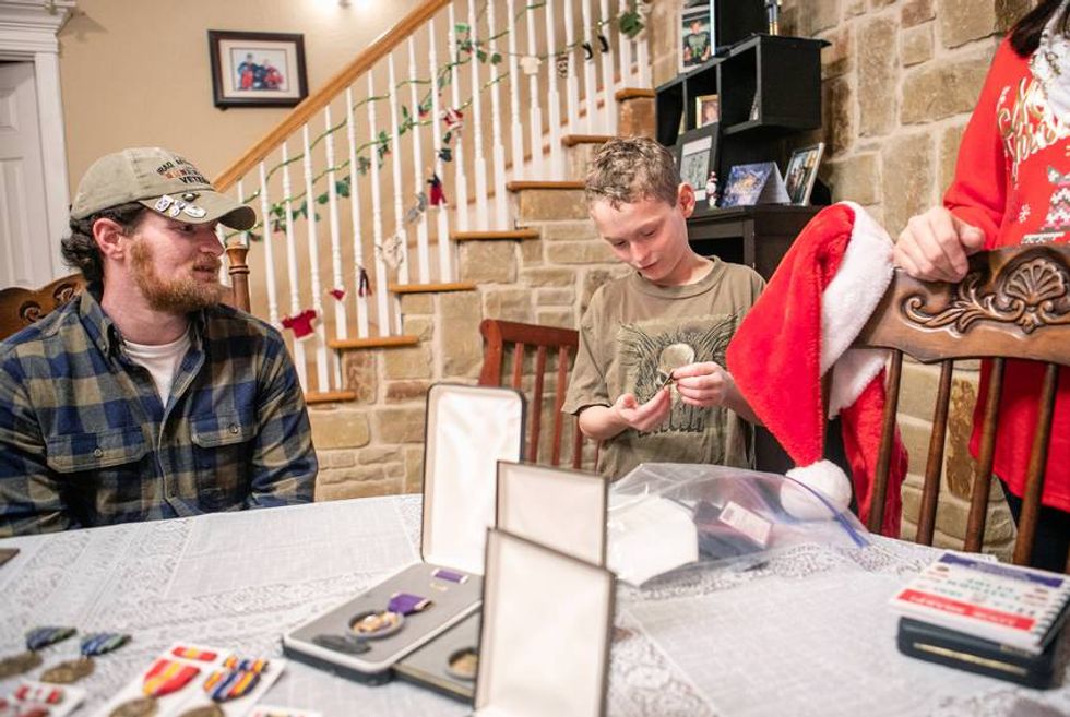 Joshua Raines (left) and his son go through the combat veteran's medals in their dining room. Raines, a medical marijuana advocate and user, served in Afghanistan and was wounded in 2010 causing severe PTSD and seizures. Photo: Leslie Boorhem-Stephenson