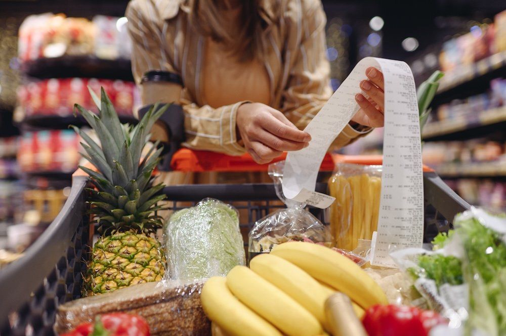 A woman grocery shopping high costs receipt