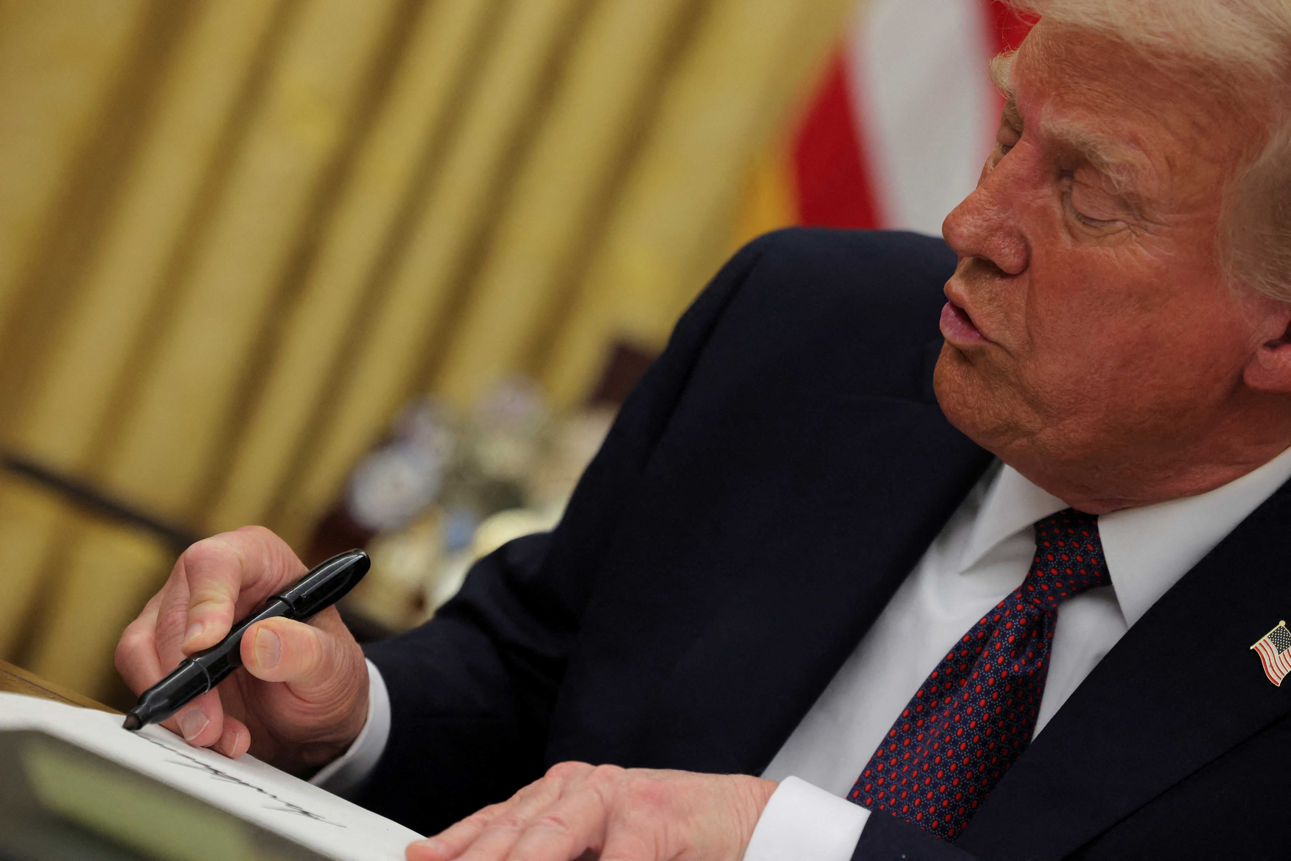 President Donald Trump signs documents as he issues executive orders and pardons in the Oval Office at the White House on Inauguration Day in Washington, January 20, 2025. REUTERS/Carlos Barria/File Photo