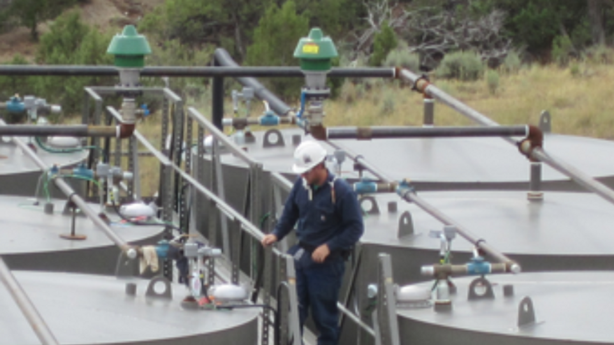 Worker preparing to gauge oil production tanks.